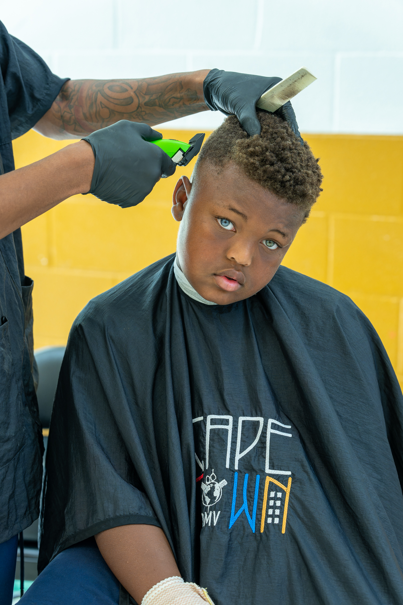 A CapeTown DMV volunteer barber gives a student a fresh haircut before the first day of school.