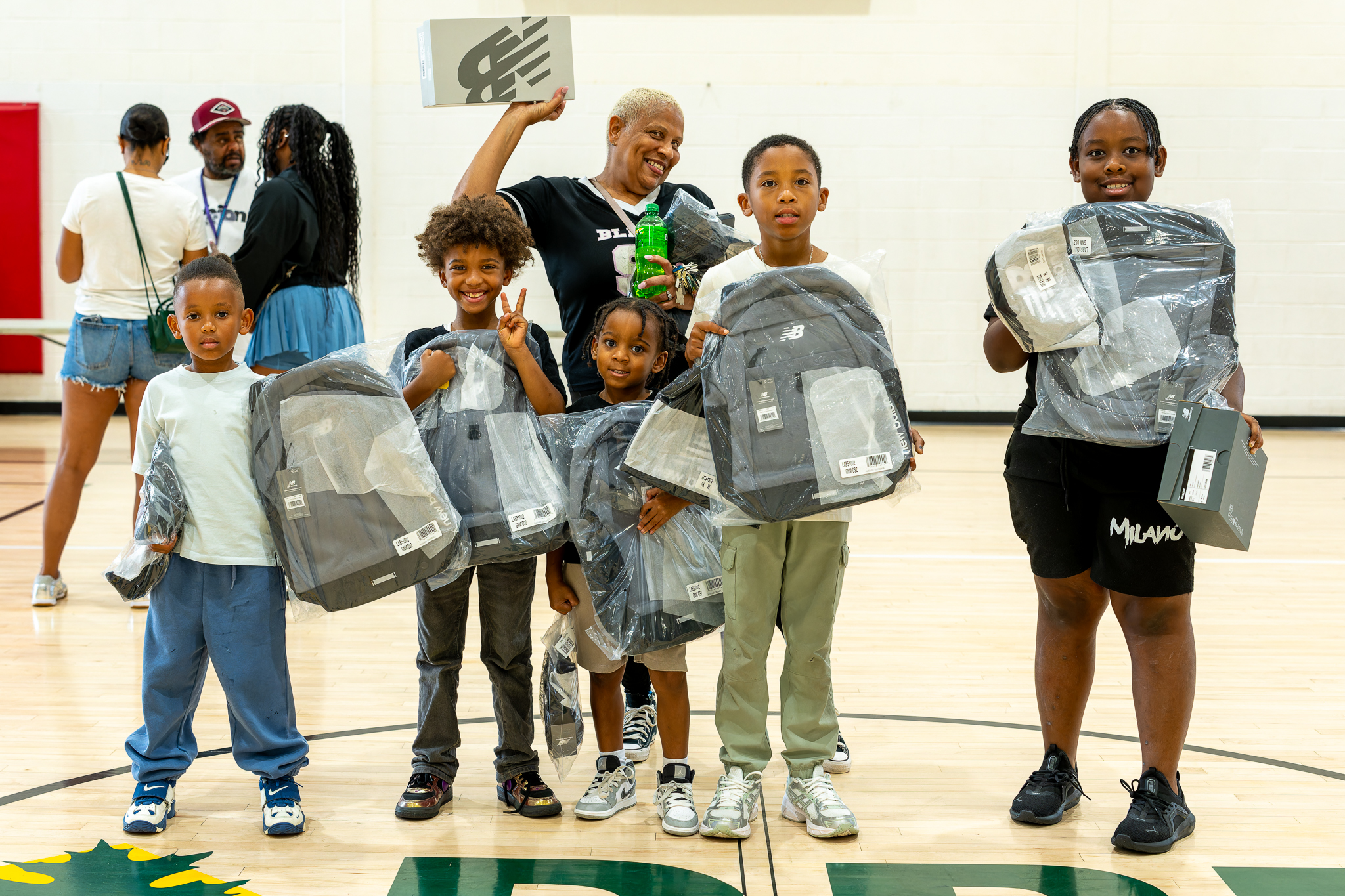Attendees display the backpacks and shoes handed out during the giveaway.